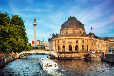 En båt på Spree-floden framför Bode-museet och Fernsehturm. En perfekt vy för din berlin reseguide.