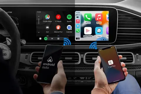 Porównanie interfejsów Android Auto i CarPlay na ekranie samochodu. Dwa telefony pokazują logo systemów, a na ekranie widać ikony aplikacji.