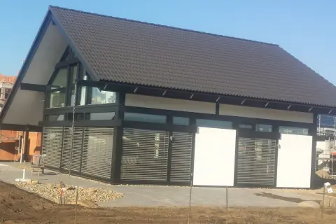 Nowoczesny dom z dużymi oknami dźwiękoszczelnymi, zadaszeniem i żaluzjami.