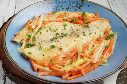 Ein zartes Rotbarschfilet mit einer cremigen Senfsauce, umgeben von julienniertem Gemüse.