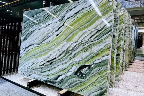 Lastre di marmo verde di prato con venature bianche e nere, esposte in un magazzino.