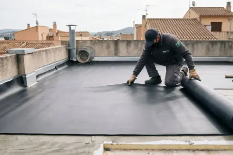 Un trabajador instala una membrana de EPDM, un material sintético de caucho, en una azotea.
