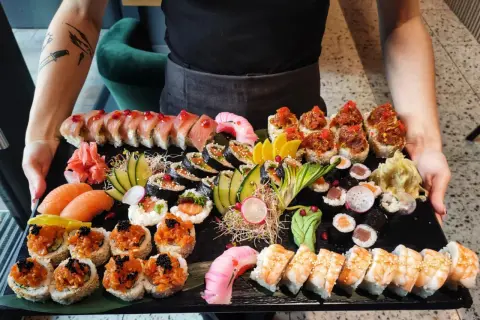 Ogromna taca z różnorodnym jedzeniem sushi: rolki z łososiem, tuńczykiem, krewetkami, a także nigiri i sashimi.