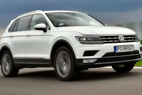 Biały Volkswagen Tiguan 2 jedzie po drodze.