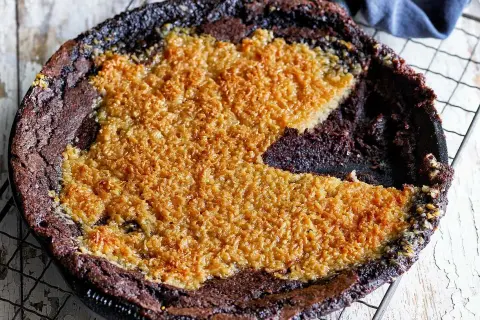 En kladdkaka med kokostosca, med en härlig seg chokladbotten och ett gyllene, krispigt kokostäcke.