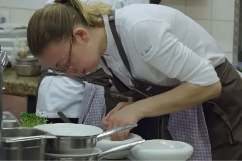 Chef prepara ingredientes en un mortero, escena digna de películas sobre cocina.