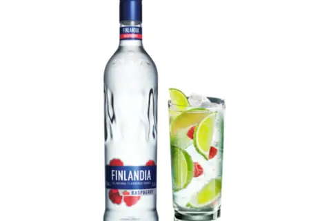 Butelka Finlandia Raspberry i szklanka z drinkiem, lodem, limonką i malinami. Idealny alkohol na letnie wieczory.
