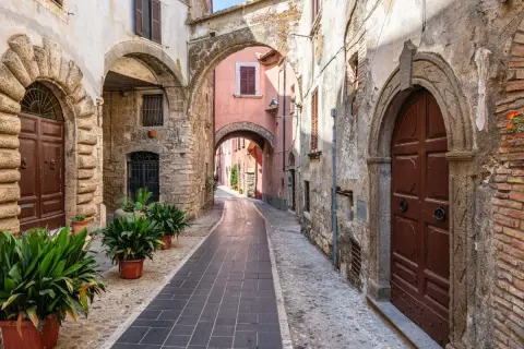 Un vicolo suggestivo a Orte, Viterbo, con archi in pietra, porte antiche e piante verdi.