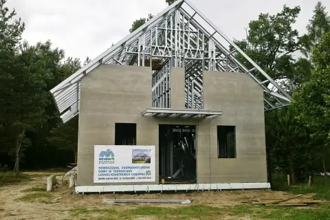 Budowa domu z konstrukcji stalowej. Widoczny szkielet dachu i ściany z otworami okiennymi.