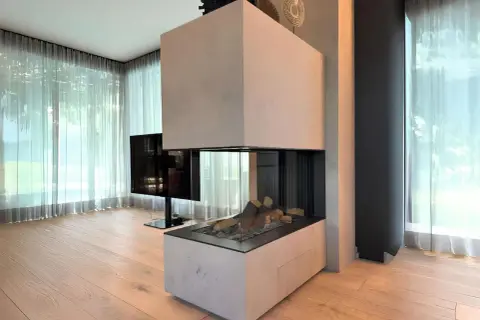 Moderner Kamin Neubau mit Glasfront und Holzelementen, umgeben von hellen Vorhängen und Holzboden.