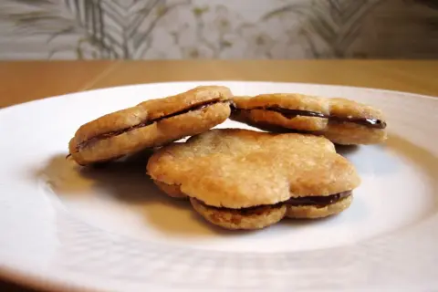Tre chokladfyllda tuile-kakor på en vit tallrik. Ett enkelt tuile recept som ger läckra småkakor.
