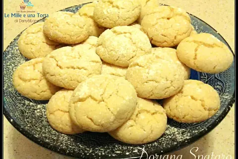 Biscotti con farina di mandorle, dorati e friabili, adagiati su un piatto scuro.