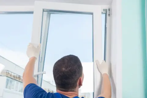 Un técnico con guantes blancos ajusta un marco para cambiar ventanas.