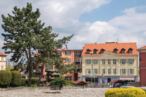 Rynek w Sobótce z kamienną rzeźbą i żółtym budynkiem.