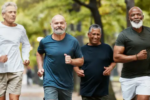 Quatre hommes d'âge mûr profitent d'une course matinale dans un parc, démontrant une excellente motricité adulte.