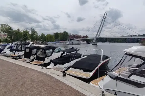 Łodzie zacumowane w porcie, z mostem w tle. Idealne miejsce, by zacząć planować, jak dojechać do Mikołajek i cieszyć się Mazurami.