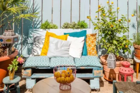 Un rincón perfecto para tus ideas chill out: un sofá de palets con cojines coloridos, plantas y faroles.