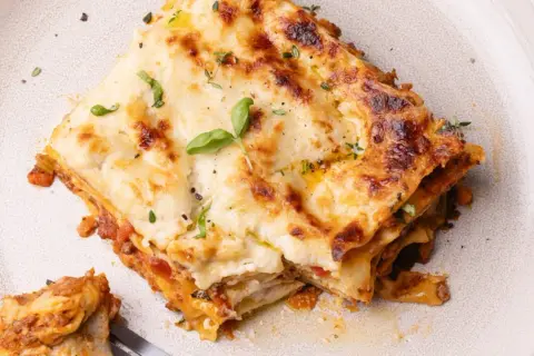 Une part de lasagne généreuse, dorée et gratinée, garnie de basilic frais. Une recette lasagne originale qui met l'eau à la bouche.