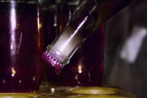 Bottiglia di vino rosso con tappo viola, una goccia cade. Il dégorgement significato è la rimozione del sedimento.