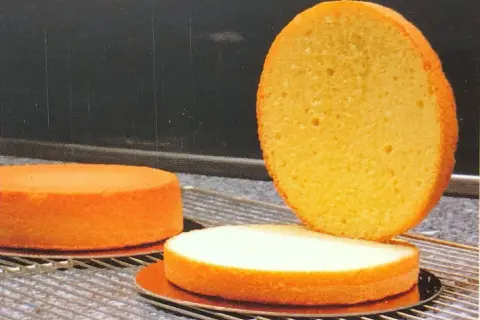 Trois disques de génoise dorée, prêts pour une recette. L'un est coupé en deux, révélant sa texture aérée.