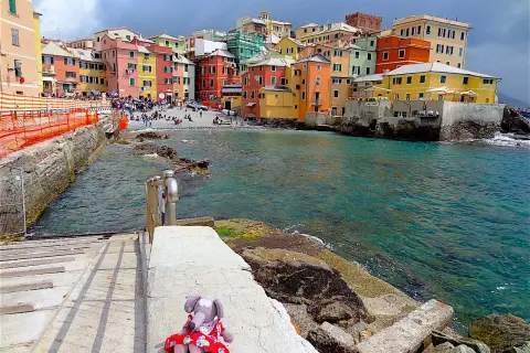 Une peluche attend sur les marches menant à la mer turquoise. Les maisons colorées de Boccadasse invitent à découvrir que faire à Gênes.