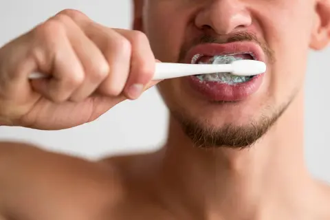 Hombre cepillándose los dientes con pasta. ¿Cuánto tiempo hay que lavarse los dientes? Dos minutos es lo recomendado.