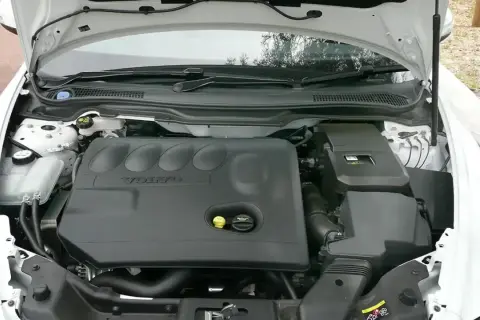 Silnik Volvo V50 2.0D z otwartą maską. Widoczna czarna pokrywa silnika z logo Volvo.