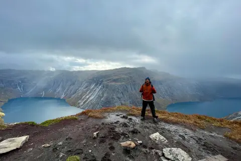Man på en klippa med en sjö och berg i bakgrunden. En lyckad trolltunga vandring!