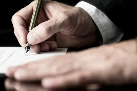 Dłoń w garniturze podpisuje dokument piórem. Druk ol9 jest gotowy do zatwierdzenia.