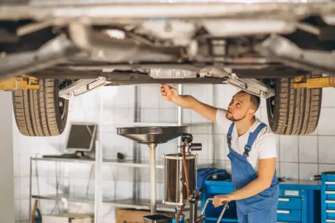 Mechanik sprawdza podwozie auta, zastanawiając się, czy regeneracja maglownicy jest bezpieczna i opłacalna.