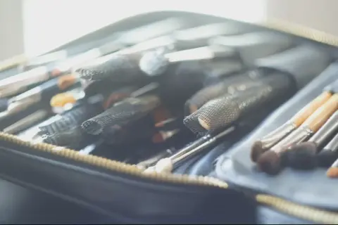 Une trousse ouverte révèle une collection de pinceaux de maquillage, prêts pour un cours de maquillage particulier.