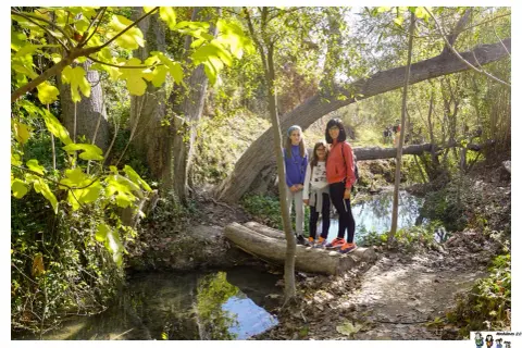 Familia posa en la ruta del agua Sella, disfrutando del sendero boscoso y el arroyo.