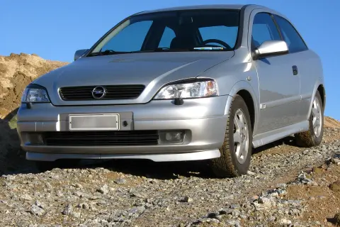 Srebrny Opel Astra G 1.6 16v na kamienistym podjeździe, gotowy na przygodę.