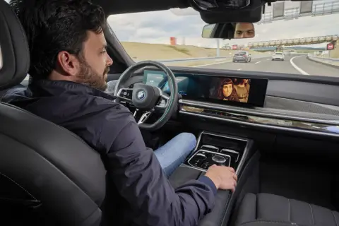 Uomo rilassato in auto, guarda un film mentre il sistema di **traffic jam assist** gestisce la guida in coda.