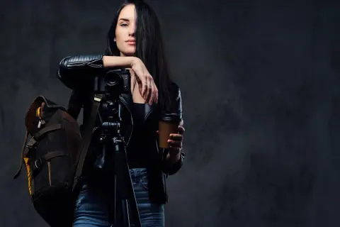 Kobieta z aparatem na statywie i kubkiem kawy, gotowa do uchwycenia niezwykłych kadrów. Opanowała zaawansowane techniki fotograficzne.