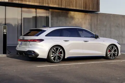 Vit Audi A5 hybrid laddas vid en laddstation. Modern design möter hållbarhet.