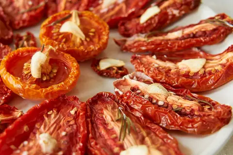 Getrocknete Tomaten mit Knoblauch und Rosmarin auf einem Teller.