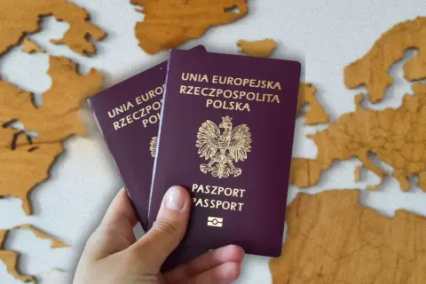 Dwa polskie paszporty w dłoni na tle mapy Europy. Zastanawiasz się, ile kosztuje paszport?