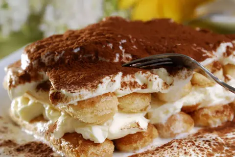 Ein Stück tiramisu originale, mit Löffelbiskuit, Creme und Kakaopulver bestäubt.