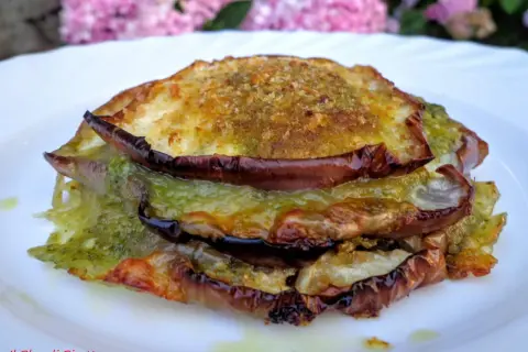Tramezzini con melanzane grigliate, pesto e formaggio fuso, un'esplosione di sapori mediterranei su un piatto bianco.