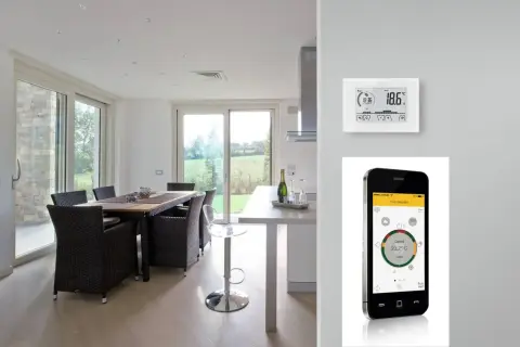 Termostato e cronotermostato: un confronto visivo. Un moderno soggiorno con tavolo da pranzo e un dispositivo di controllo della temperatura, accanto a uno smartphone che mostra un'app per la gestione della casa.