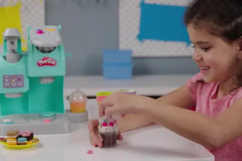 Dziewczynka bawi się w play doh kawiarnia, tworząc pyszne desery z plasteliny.