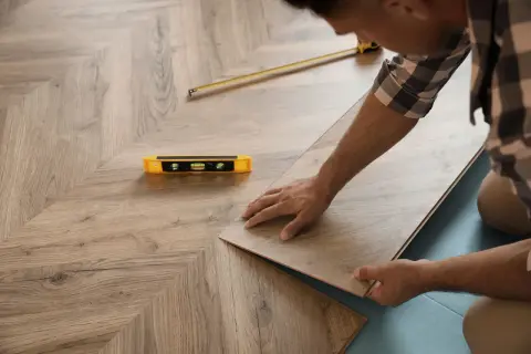 Installazione di un nuovo pavimento in laminato, posato come massetto sopra pavimento esistente. Livella e metro a nastro a portata di mano.