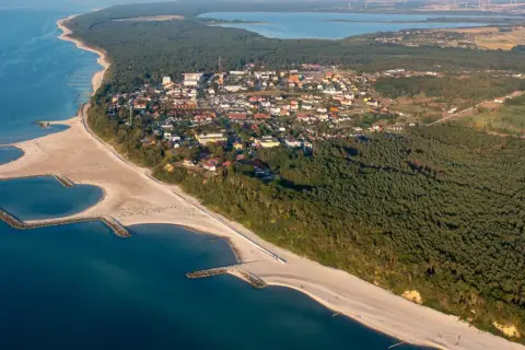 Widok z lotu ptaka na nadmorską miejscowość z plażą, lasem i zatoczkami. Jezierzany atrakcje czekają!