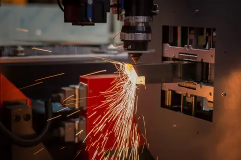 Precyzyjne cięcie metalu przez laser. Iskry sypią się z miejsca obróbki, tworząc widowiskowy otwór technologiczny.