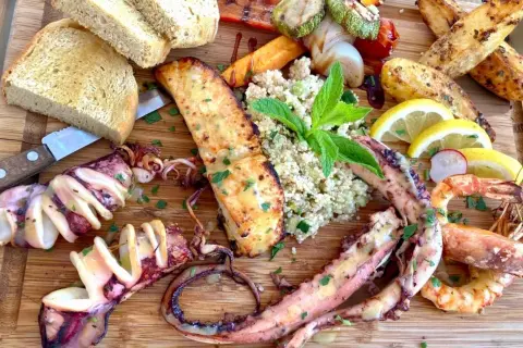 Wyśmienite greckie jedzenie: grillowane kalmary, krewetki, łosoś, pieczone ziemniaki, kasza i pieczywo.
