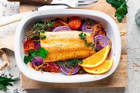 Saftiger Kabeljau im Ofen mit roten Zwiebeln, Tomaten, Kräutern und Orangenscheiben.