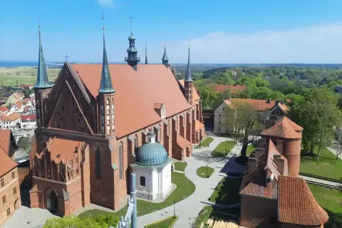 Widok z góry na Frombork zamek i katedrę. Czerwona cegła, zielone dachy i błękitne niebo tworzą malowniczy krajobraz.