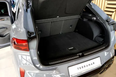Otwarty bagażnik szarego SUV-a Cupra Terramar z widocznym wnętrzem i tablicą rejestracyjną.