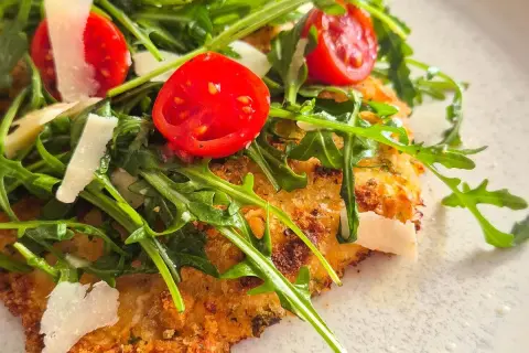 Knuspriges paniertes Hähnchen mit Rucola, Kirschtomaten und Parmesan.